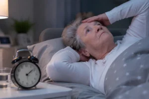 Idosa acordada durante a noite representando a insônia na terceira idade.